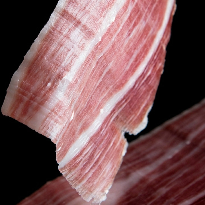 Fina loncha de jamón ibérico 100% Raza Ibérica cortada a cuchillo por un maestro jamonero.